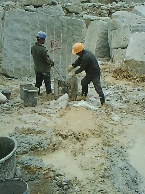 Worker filling static cracking agent into holes for reinforced concrete demolition